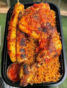 image of nigerian smoky jollof rice served with roasted plantain and chicken lap