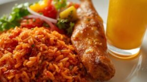 image of party jollof rice in a plate served with salad and chicken with a cup of fresh juice by the side